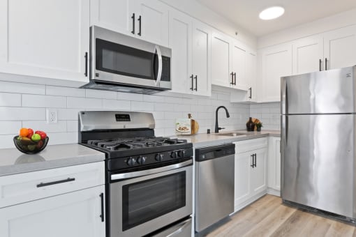 a kitchen with white cabinets and stainless steel appliances