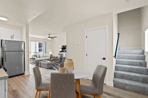 a dining area with a table and chairs and a staircase in the background