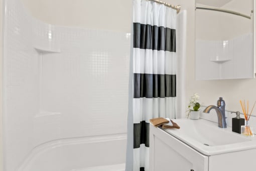 a white bathroom with a black and white shower curtain