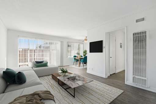 A living room with a white couch, a coffee table, and a television.