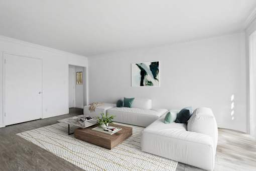 A white couch with green pillows sits in a room with a coffee table in front of it.