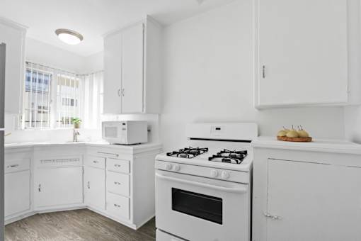 A white kitchen with a stove, oven, and microwave.