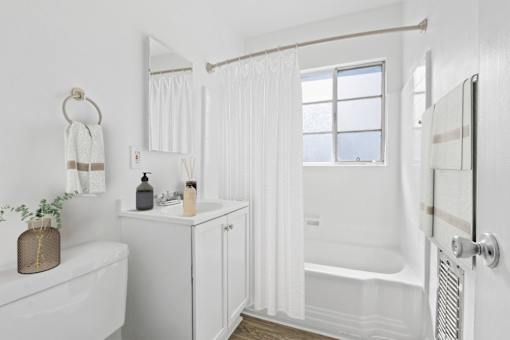 A white bathroom with a tub, sink, and mirror.