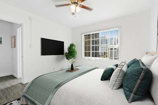 A bedroom with a bed, pillows, and a television.