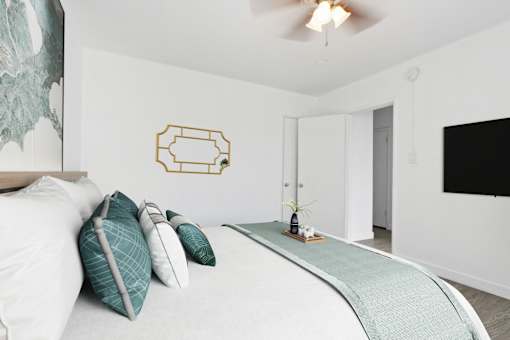 A bedroom with a bed, pillows, and a decorative mirror on the wall.