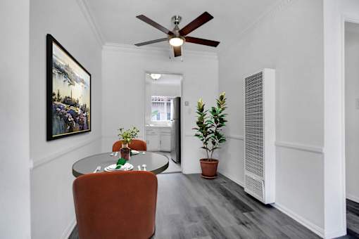 A room with a ceiling fan and a painting on the wall.