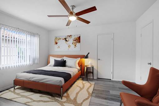 A bedroom with a bed, a chair, and a ceiling fan.