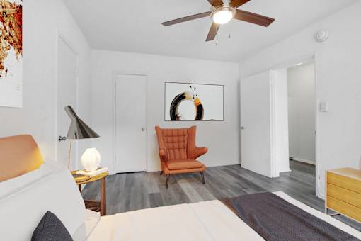 A bedroom with a bed, a chair, and a ceiling fan.