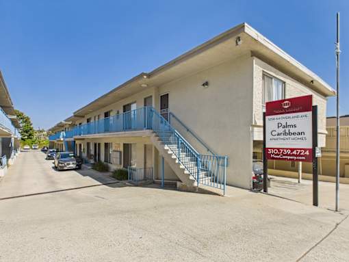 A building with a sign that says Palms Caribbean Apartment Homes.