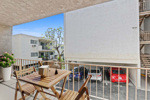 a balcony with a table and chairs and a parking lot