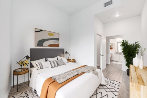 a white bedroom with a large bed and a bathroom