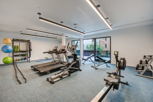 a gym with treadmills and other exercise equipment in a building with windows