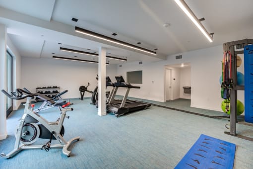 a gym with cardio equipment and weights in a building with white walls