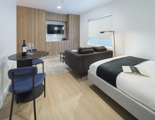 a hotel room with a bed and a table with a bottle of wine