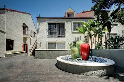 A courtyard with a fountain and a building in the background.