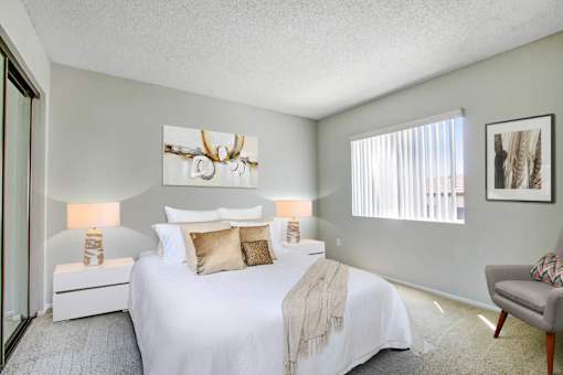 A bedroom with a large bed and a chair.