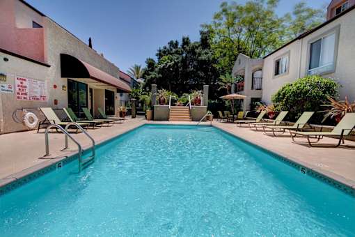 A swimming pool surrounded by lounge chairs and umbrellas.