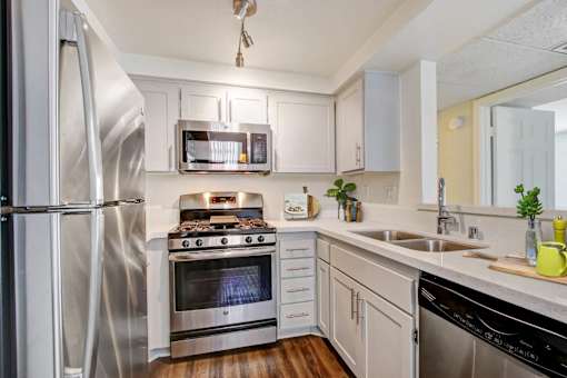 A modern kitchen with stainless steel appliances and wooden floors.
