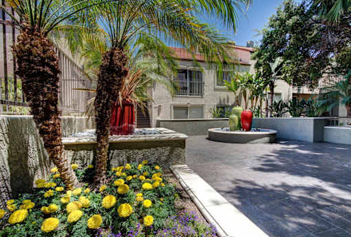 A garden with yellow flowers and a red object in the middle.