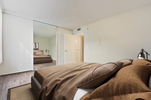 a bedroom with white walls and a large bed with brown pillows