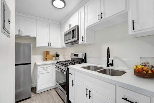 A modern kitchen with white cabinets and stainless steel appliances.