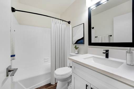 A white bathroom with a toilet, sink, and shower.