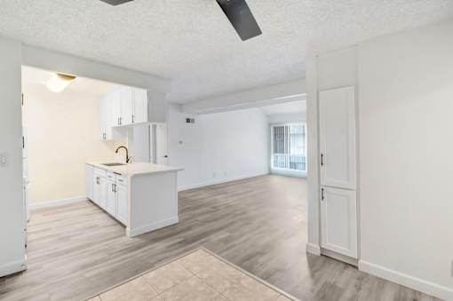 A kitchen with white cabinets and a ceiling fan.