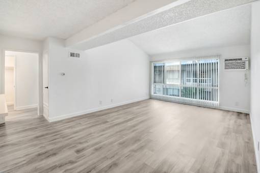 A room with wooden flooring and a window with blinds.