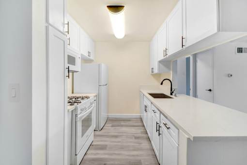 A kitchen with white cabinets and appliances.