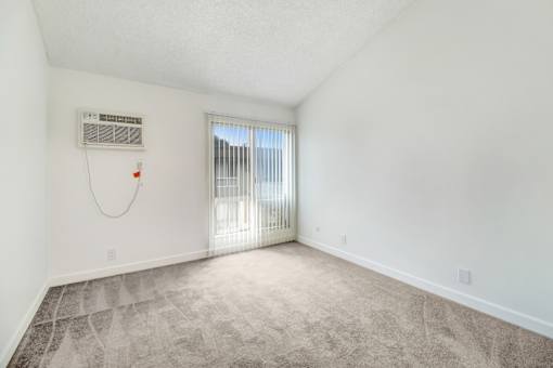 A room with a window covered by blinds and a wall-mounted air conditioner unit.