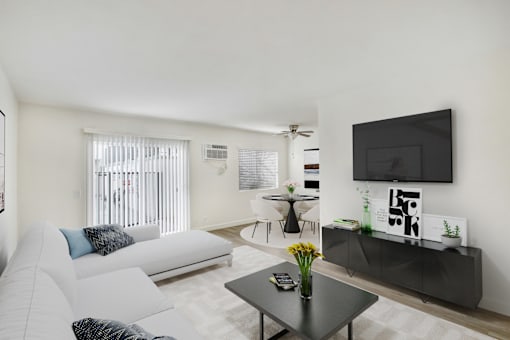 A living room with a white couch, a black coffee table, and a flat screen TV mounted on the wall.