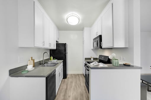 A kitchen with black appliances and white cabinets.