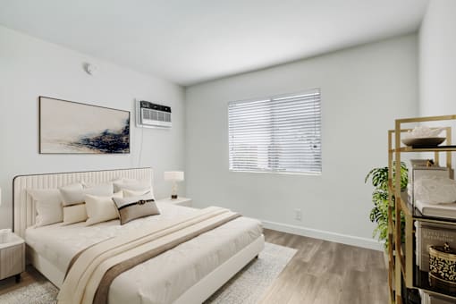 A bedroom with a large bed and a painting on the wall.