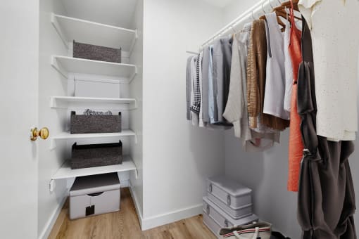 a small walk in closet with shelves and a rack of clothes