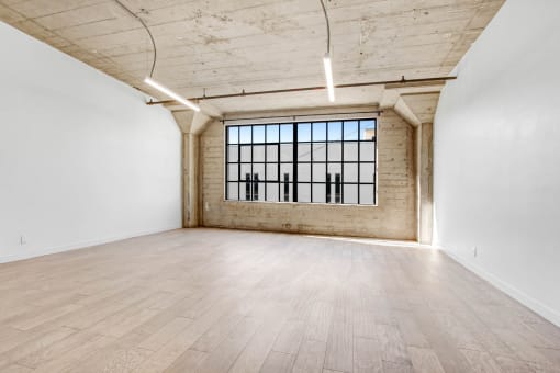 an empty room with wood floors and a large window