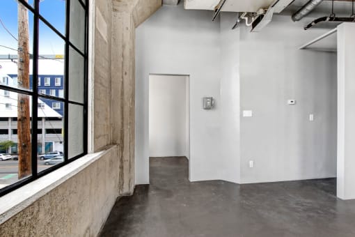 a large window in a room with concrete floors and a door at the end of the room