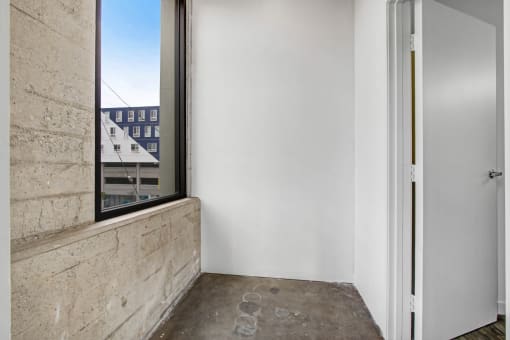 a bedroom with a large window and a concrete wall