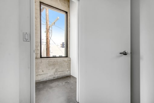 a white door with a window in a room with concrete floors and a brick wall