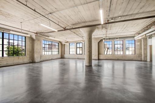 an empty room with large windows and a concrete floor