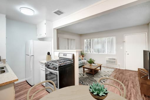 an open kitchen and living room with a dining table and a refrigerator
