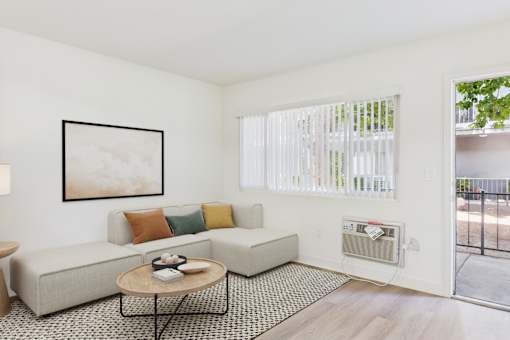 A living room with a couch, a coffee table, and a painting on the wall.
