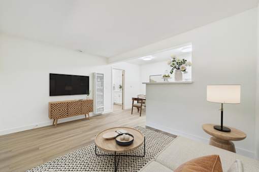 A living room with a television, a bench, a coffee table, and a lamp.