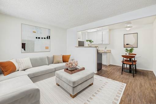 A living room with a grey sofa, a white coffee table, and a wooden floor.