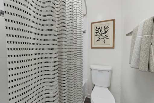 A white toilet in a bathroom with a white shower curtain.
