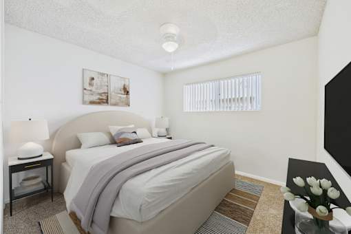 A bedroom with a large bed and a nightstand with a lamp.
