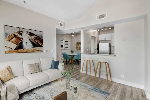 A living room with a white couch and a painting of boats on the wall.