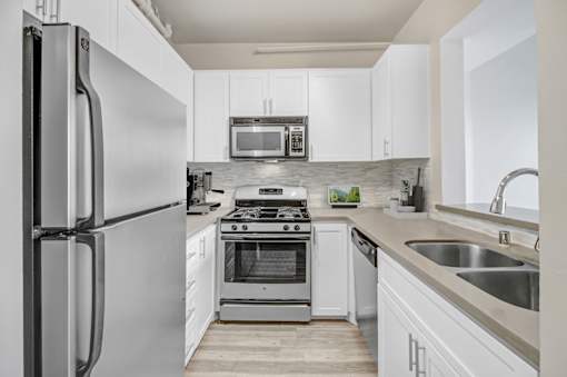 A modern kitchen with a refrigerator, stove, and microwave.
