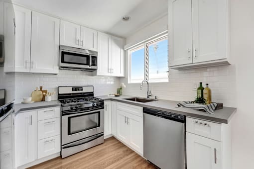 A kitchen with white cabinets and stainless steel appliances.