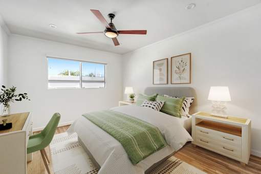 A bedroom with a bed, desk, chair, and window.