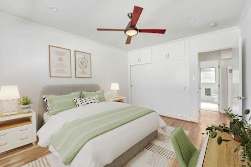 A bedroom with a bed, a ceiling fan, and a green chair.